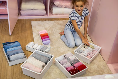 High angle view of girl arranging clothes in container