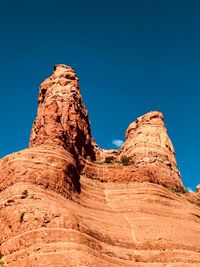 Low angle view of rock formation against clear blue sky