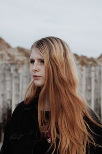 Beautiful young woman standing against sky