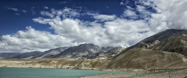 Scenic view of mountains and lake against cloudy sky