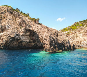 Rock formations by sea against blue sky