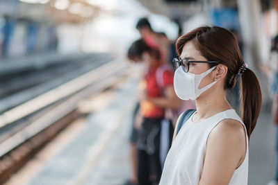 Side view of woman wearing flu mask standing outdoors