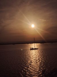 Silhouette sailboat in sea against sky during sunset