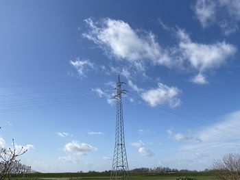 Low angle view of electricity pylon on field against sky