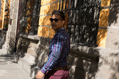 Young man by building on sidewalk