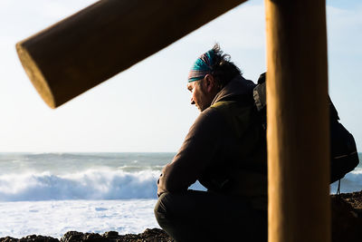 Side view of man sitting on beach