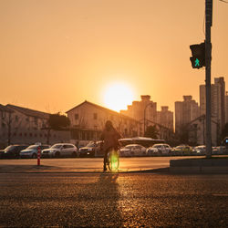 Cars on road at sunset while pedestrian trying to cross the road in bicycle i. sunset