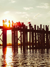 Silhouette pier over sea against sky during sunset