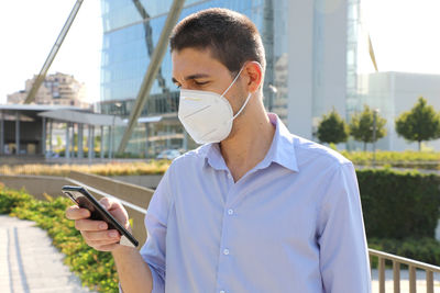 Man using mobile phone against buildings