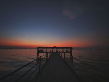 Pier over sea against sky during sunset