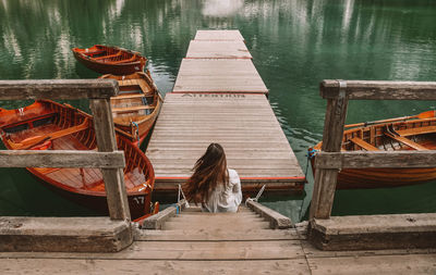 Woman sitting on pier over lake 