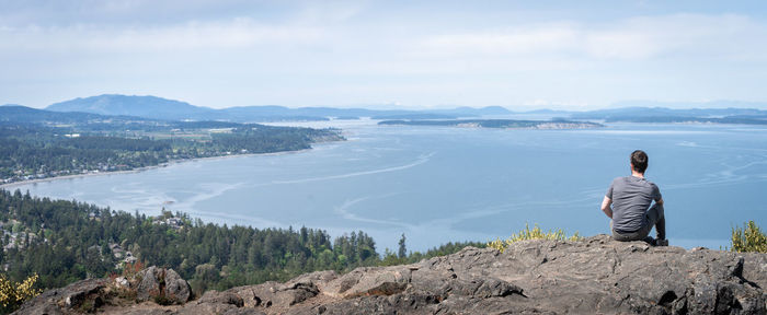 Young man enjoying panoramic view on island and surrounding ocean, vancouver island, bc, canada