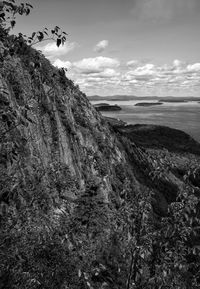 Scenic view of sea by mountain against sky