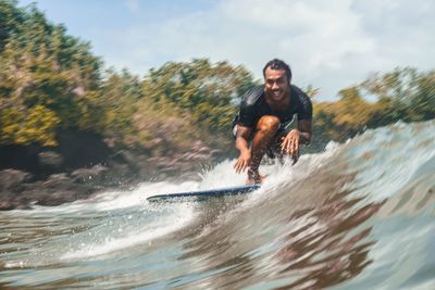 Cheerful man surfing against sky