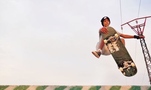 Low angle view of young man jumping against sky