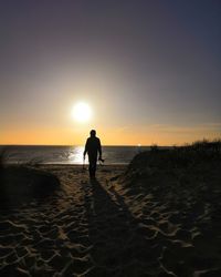 Silhouette people on beach against sky during sunset