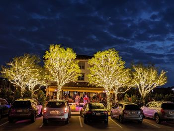 Cars on illuminated street against sky at night