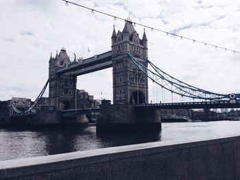 Bridge over river against cloudy sky