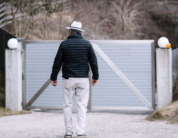 A man walking to his automatic gate, coming home from work, the security and safety of his own home