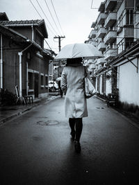 Rear view of people walking on road in city