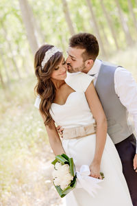 Couple romancing with bouquet while standing outdoors