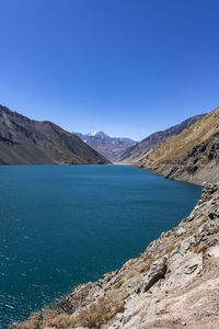 Scenic view of lake and mountains against clear blue sky