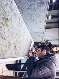 Young woman photographing while standing against white background