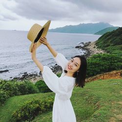 Young woman standing by sea against sky