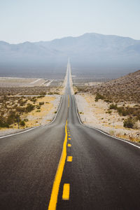 Road leading towards mountains against sky