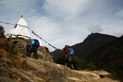 Rear view of people walking on rock against sky