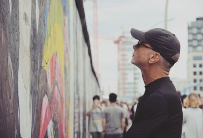 Man looking at graffiti on wall while standing in city