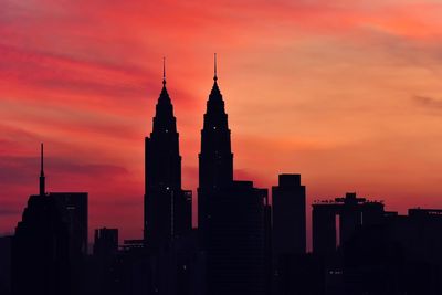 Silhouette of buildings against cloudy sky during sunset