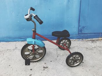 Bicycle parked on footpath against blue wall