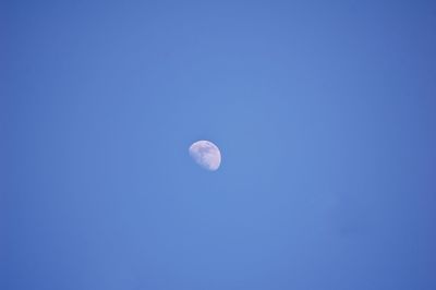 Low angle view of moon against clear blue sky