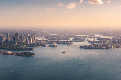 Aerial view of sea and buildings against sky during sunset