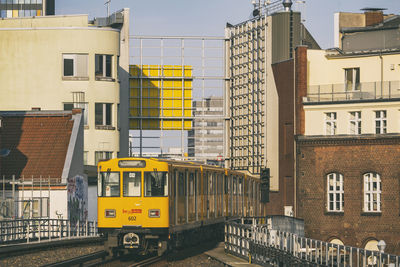 Buildings by railroad tracks in city against sky