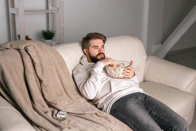 Full length of man relaxing on sofa at home