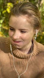 Girl smiles headphones drinking coffee and tea from an iron cup listening music under the tree 