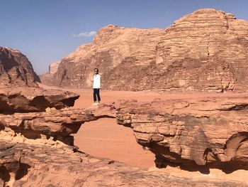 Woman standing on rock formation against sky