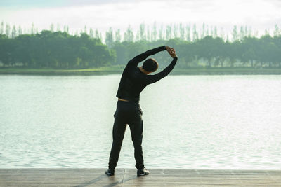 Rear view of man standing in lake against sky
