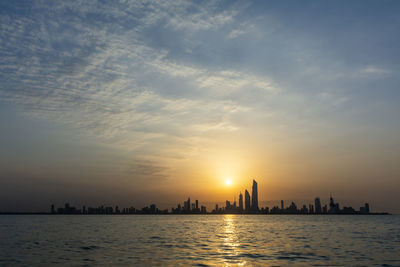 Scenic view of sea and buildings against sky during sunset