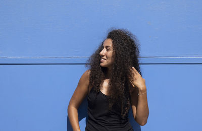 Beautiful young arabic woman standing against blue wall