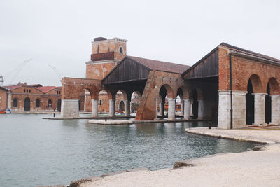 View of old building by river against sky