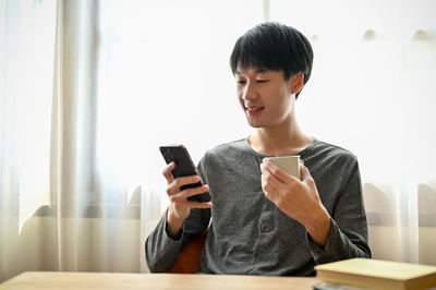 Young woman using mobile phone while sitting at home