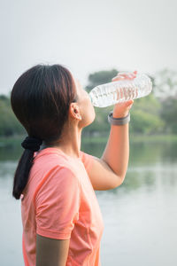 Midsection of woman drinking water from lake