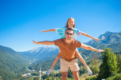 Woman with arms outstretched against mountain range