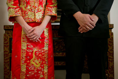 Midsection of wedding couple standing by table during ceremony