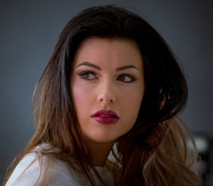 Close-up portrait of young woman against gray background