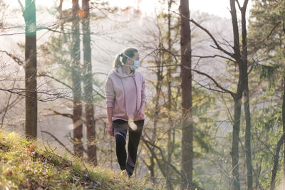 Woman wearing mask standing in forest
