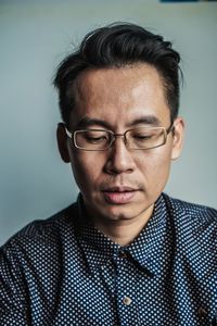 Close-up of thoughtful man wearing eyeglasses against gray background